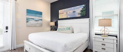 A bedroom with a bed, nightstands, a painting, and a window with blinds.