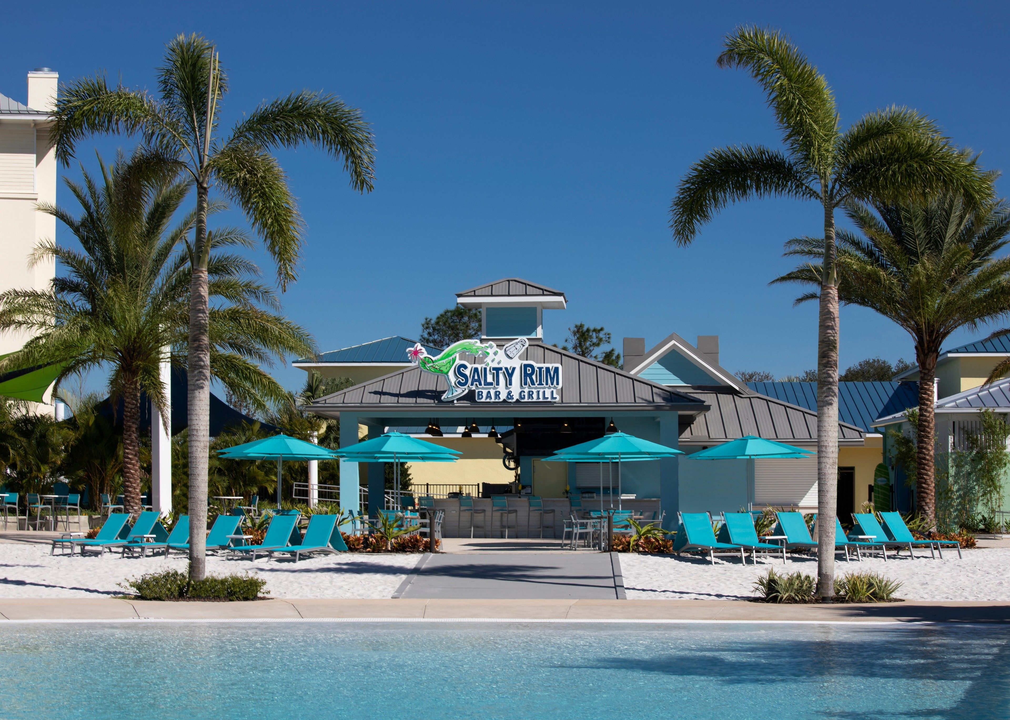 A pool area with a bar named "Salty Rim Bar & Grill" and several lounge chairs.