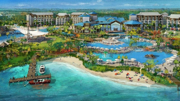 Un complexe hôtelier comprenant plusieurs bâtiments, un espace piscine central, une plage et un quai avec un bateau.
