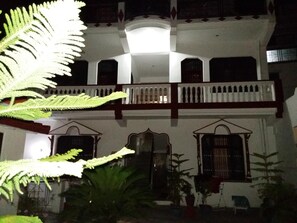A two-story building with a balcony and large windows. - Sonu Guest House - Hostel (Yamkeshwar)