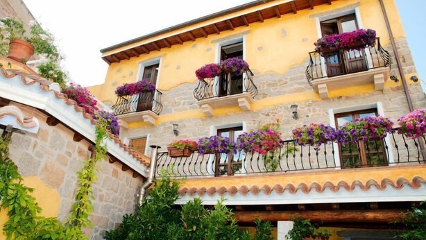 A multi-story building with balconies adorned with flower boxes. - L' affittacamere Funtanedda (Teti)