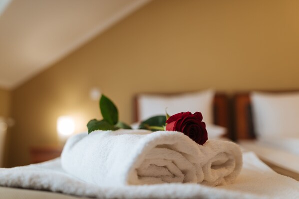 A neatly folded white towel with a red rose on a hotel bed. - Areo Hotel & Restaurant (Odorheiu Secuiesc)