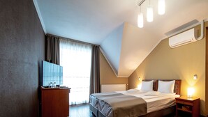 A bedroom with a bed, bedside tables, a TV, and a window with curtains. - Areo Hotel & Restaurant (Odorheiu Secuiesc)