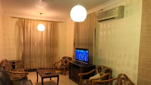 A living room with a sofa, armchairs, a coffee table, and a television. - Sea View Luxury Furnished Flat (Aqaba)