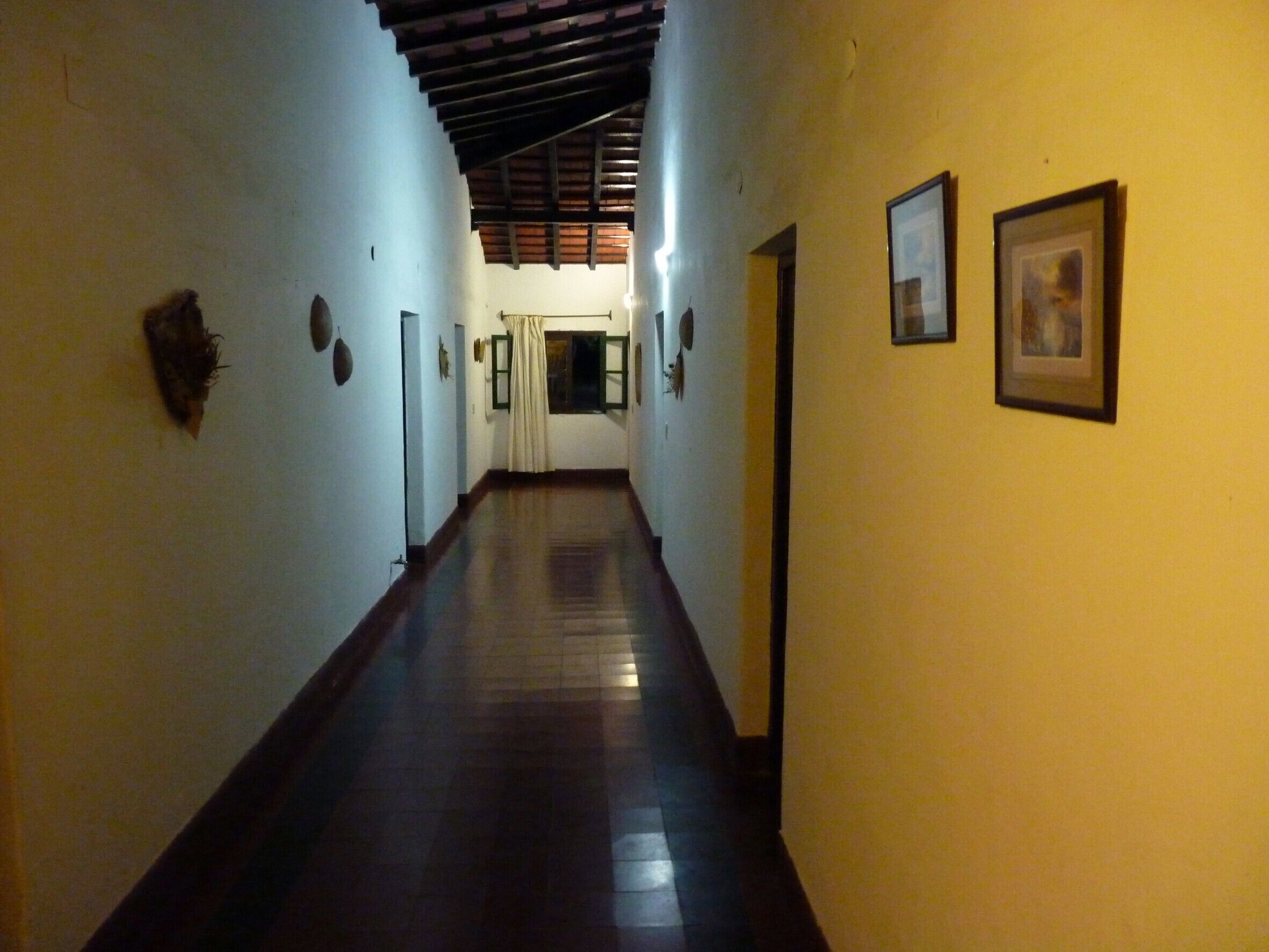 Un pasillo con pisos de madera y paredes blancas, que conduce a una puerta al final.