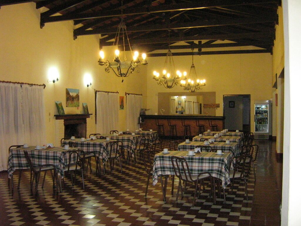 A dining area with checkered flooring, tables with plaid tablecloths, and hanging chandeliers.