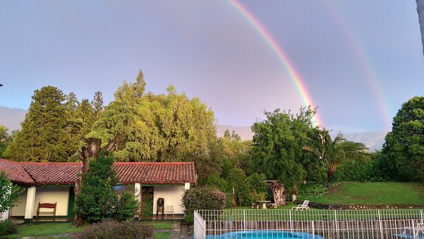 A house with a red-tiled roof, a swimming pool, and lush greenery. - Hotel Colonial (Merlo)