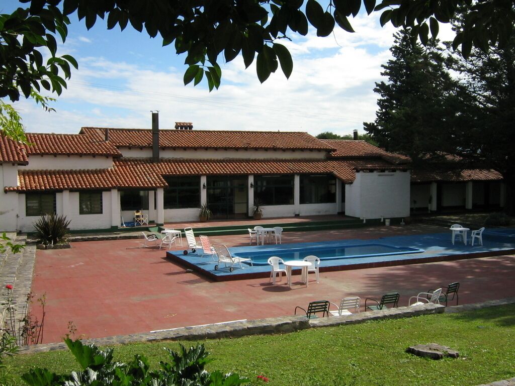 A building with a tiled roof, a swimming pool, and outdoor seating.