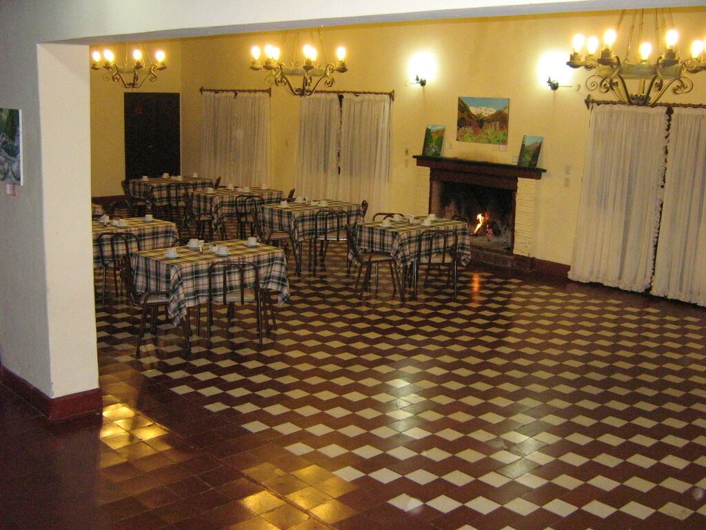 A dining area with checkered flooring, tables with plaid tablecloths, and a fireplace.