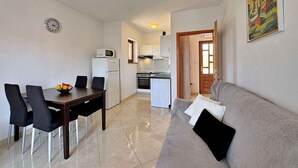 A compact living space with a dining area, kitchenette, and a sofa. - Holiday apartment with balcony and sea view (Šilo)
