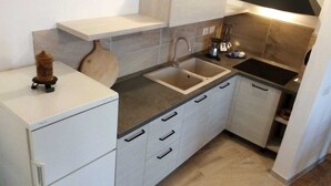A compact kitchen with white cabinets, a double sink, and a small countertop. - QUIET APARTMENT FOR LOVERS OF THE LAKE AND MOUNTAIN TREKKING (Pigra)