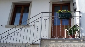 A building with a metal staircase, a wooden door, and a window. - QUIET APARTMENT FOR LOVERS OF THE LAKE AND MOUNTAIN TREKKING (Pigra)