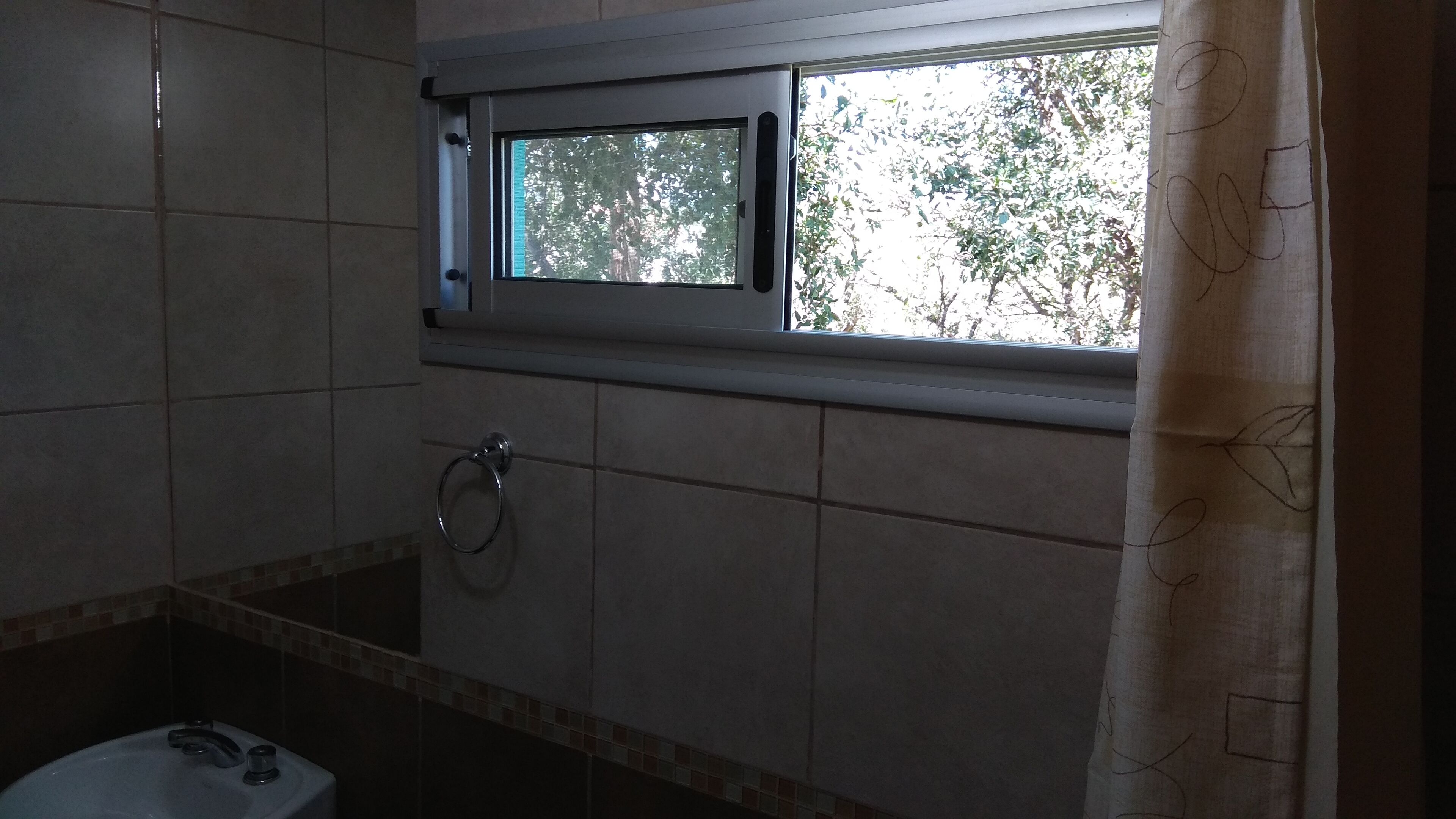 A bathroom with a window, a towel ring, and a sink.
