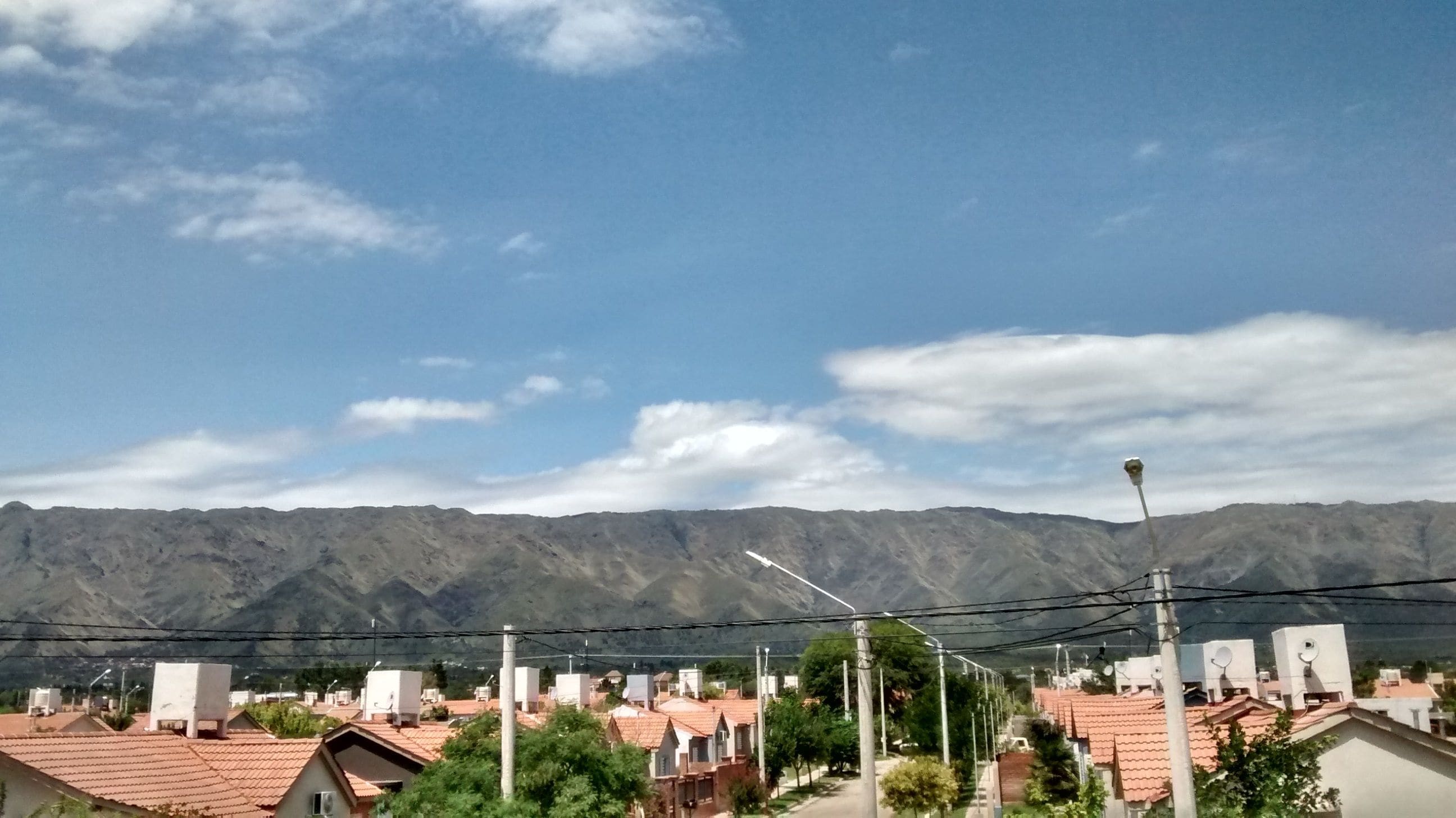 Un barrio residencial con casas, una calle y montañas al fondo.