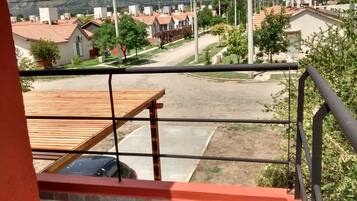 A residential area with houses, a paved road, and a view from a balcony with a wooden deck.