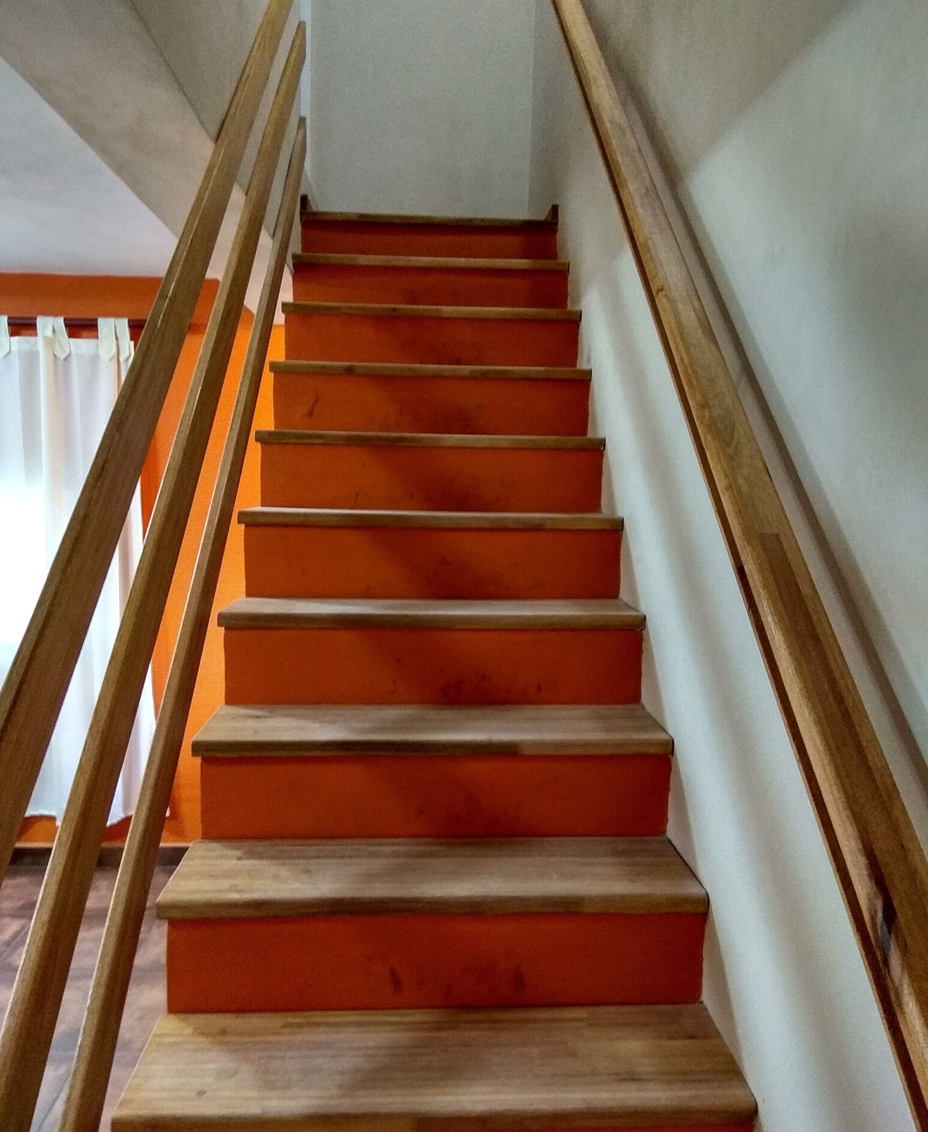 Una escalera de madera con escalones anaranjados que conducen a una plataforma.