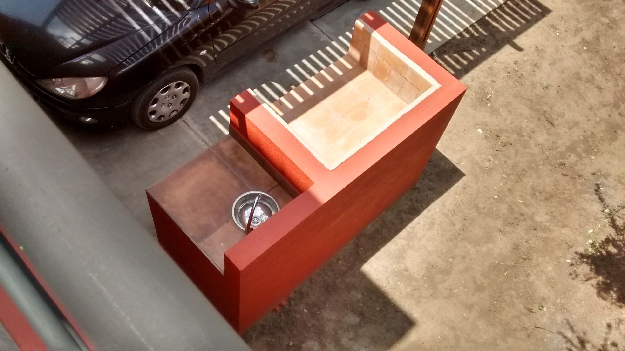 A red bench with a metal bowl and a wooden seat.