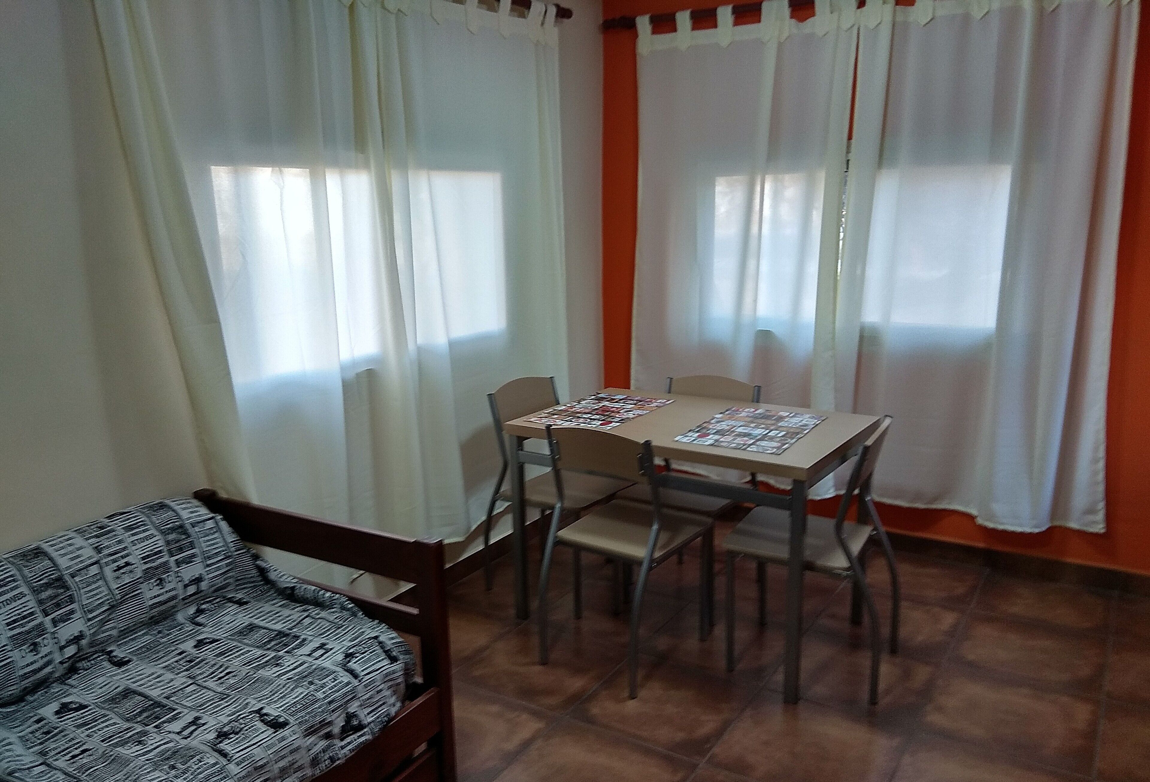 Un comedor con una mesa y sillas, un sofá y cortinas.