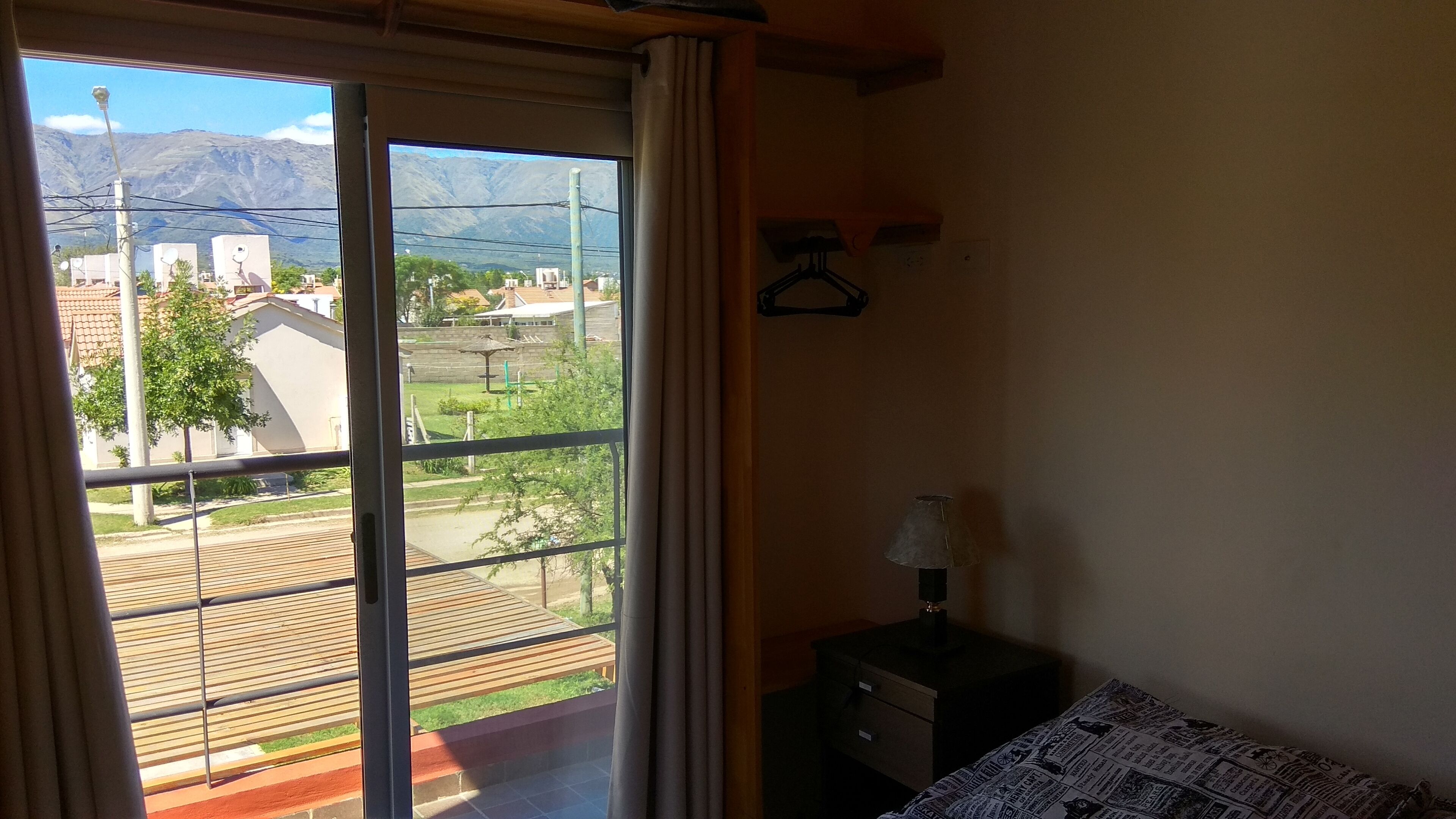 Una habitación con un ventanal amplio que ofrece vistas a una zona residencial y montañas.