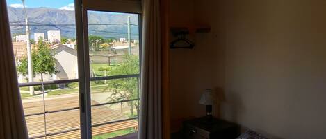 Una habitación con un ventanal amplio que ofrece vistas a una zona residencial y montañas.