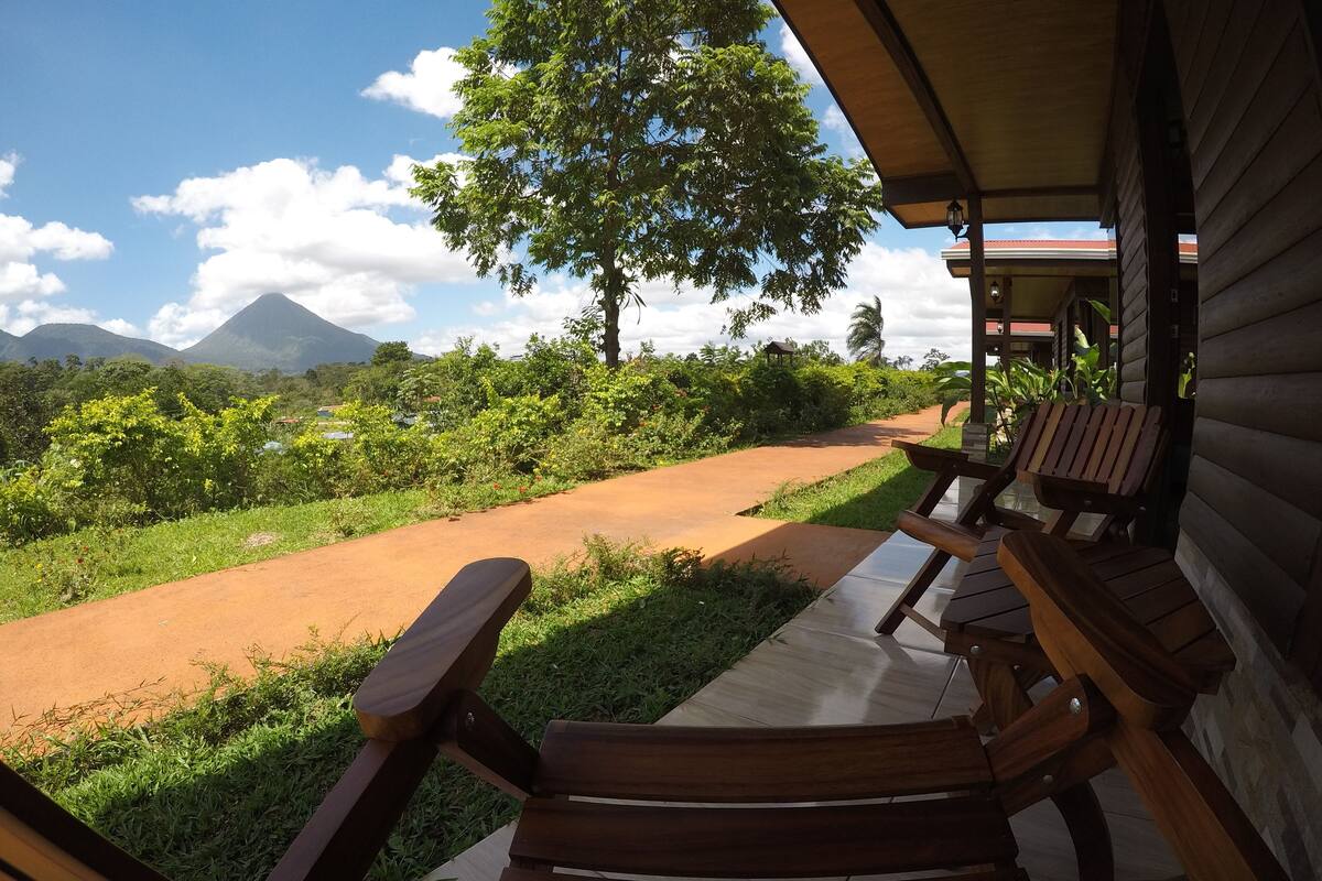 A wooden deck with benches overlooking a scenic landscape with a mountain in the distance.