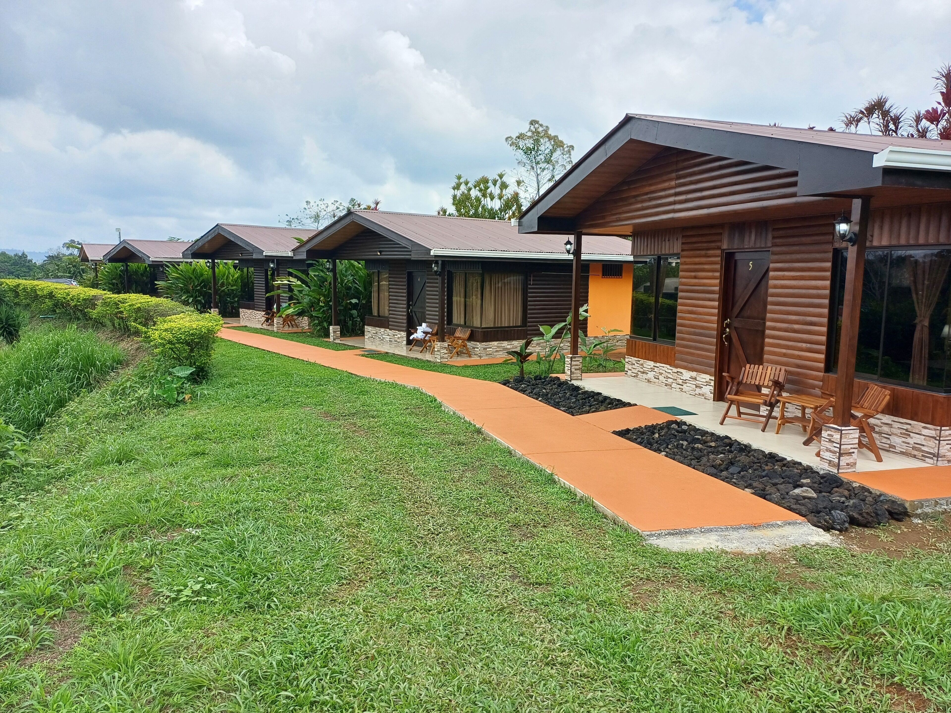 Een rij moderne vakhuizen met een verhard pad, buitenmeubels en een aangelegde tuin.