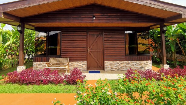 Uma cabana de madeira com telhado inclinado, porta de madeira e um banco na parte externa.