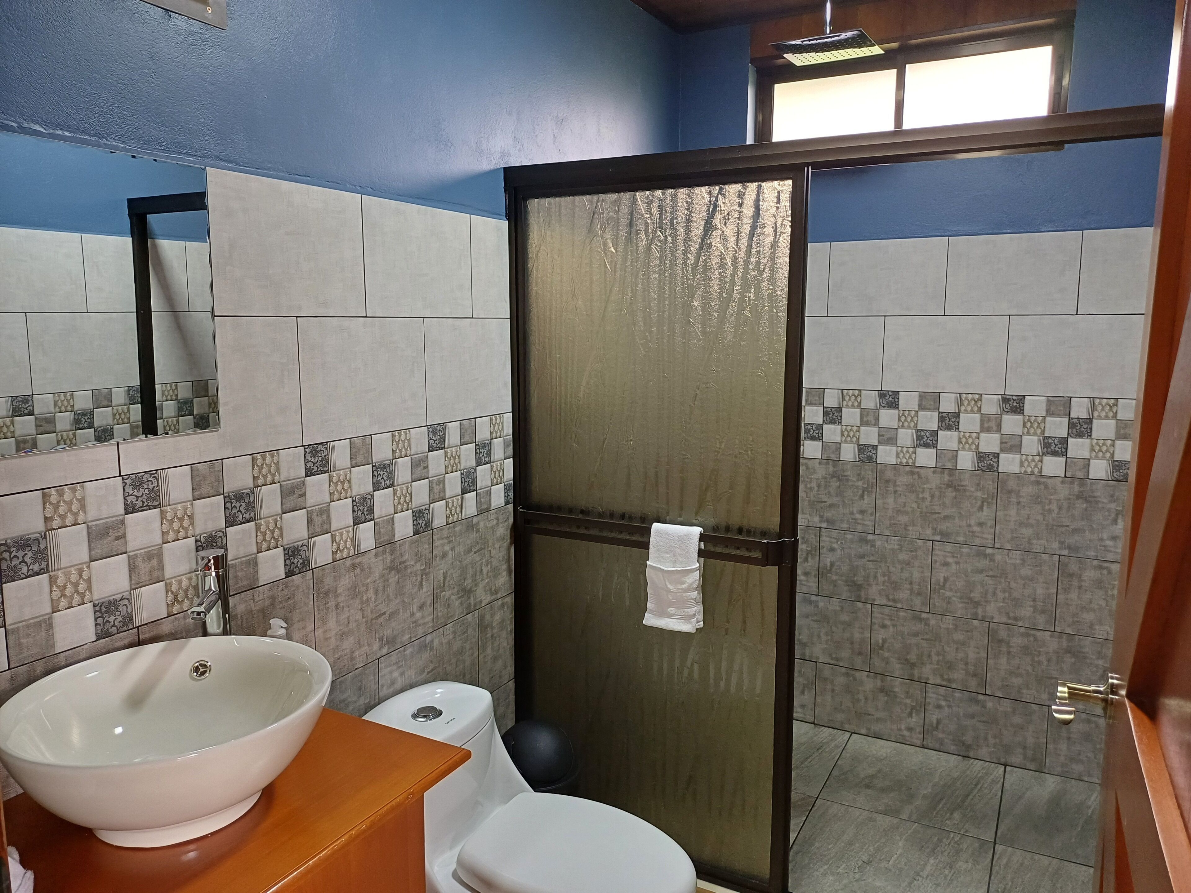 Un baño con lavamanos blanco, inodoro y puerta de ducha de vidrio.