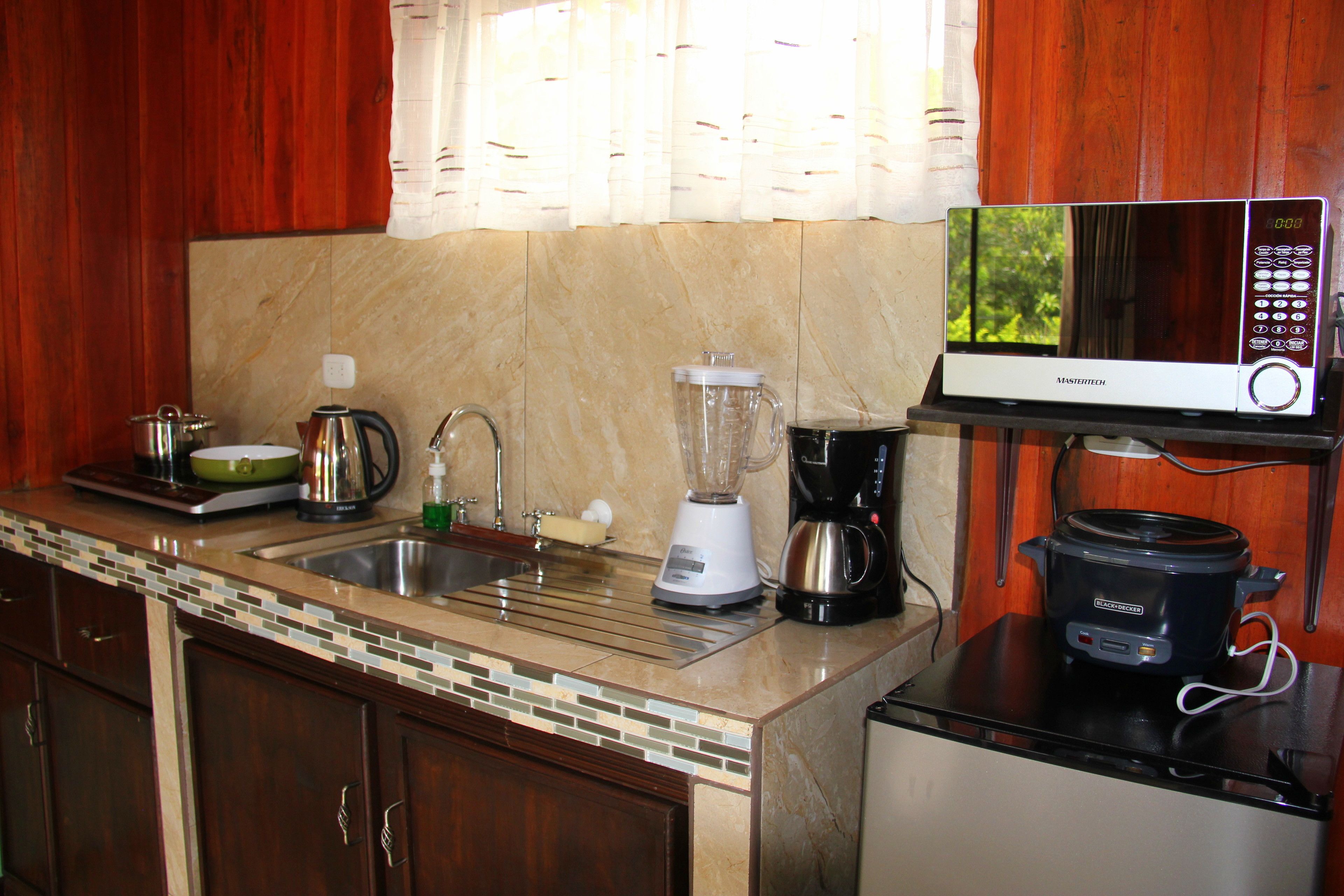 A kitchen with a microwave, blender, coffee maker, and slow cooker on the counter.