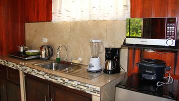 A kitchen with a microwave, blender, coffee maker, and slow cooker on the counter.