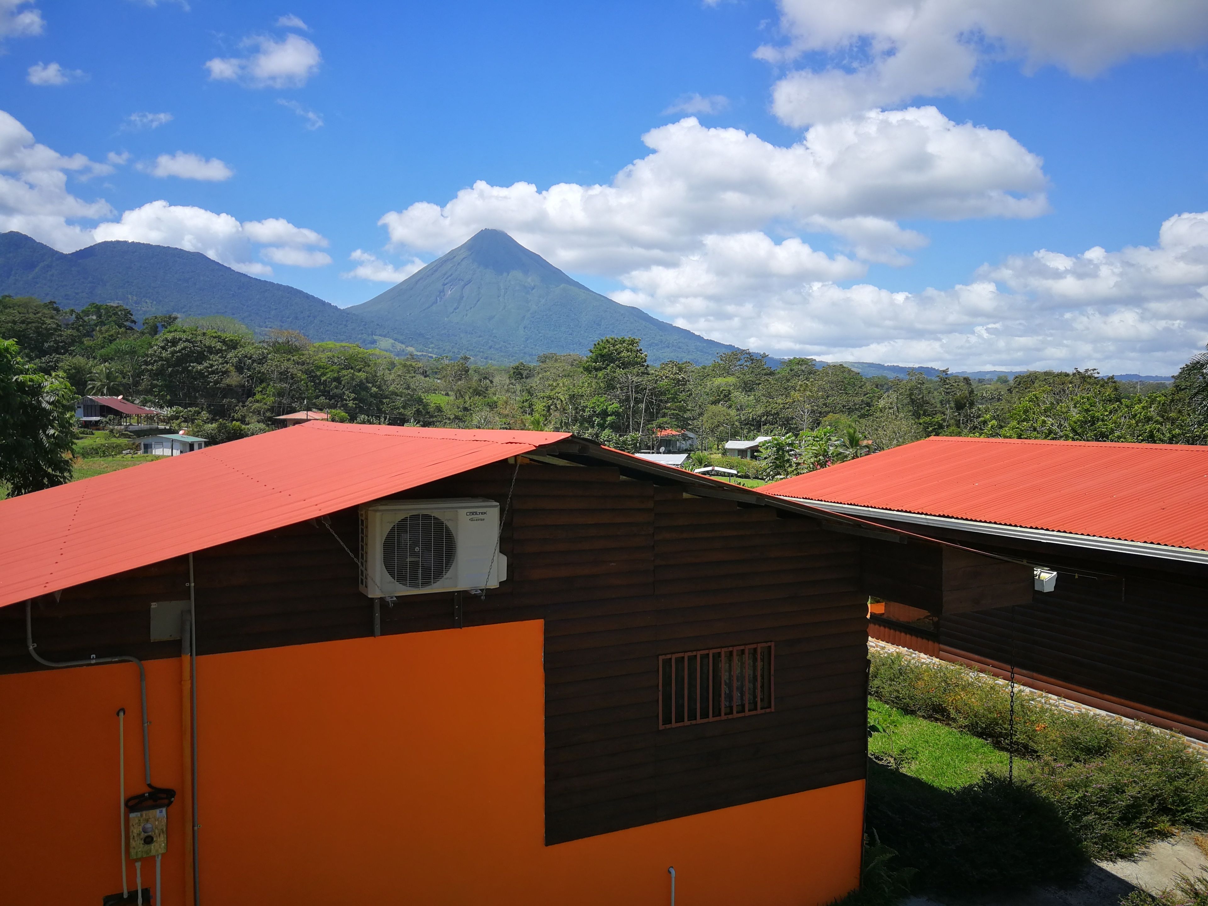 A view of a mountain with a red-roofed building in the foreground.