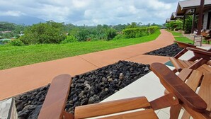 Uma trilha leva a um edifício com área externa para sentar e vista para vegetação e colinas ao longe.