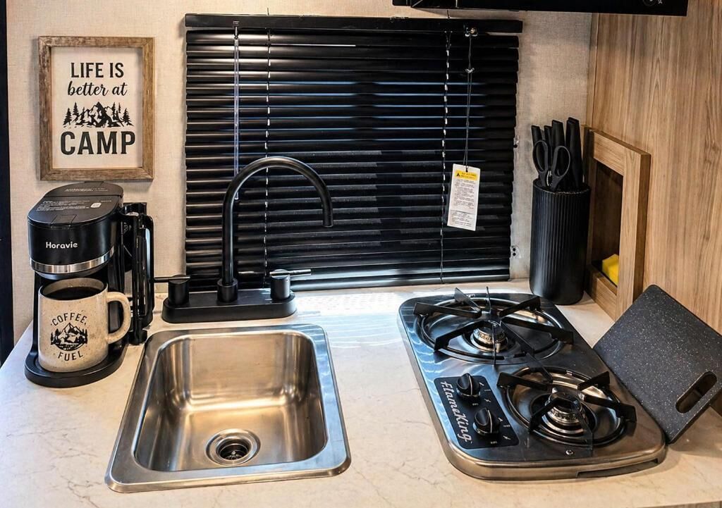 Uma cozinha compacta com pia, fogão e cafeteira.