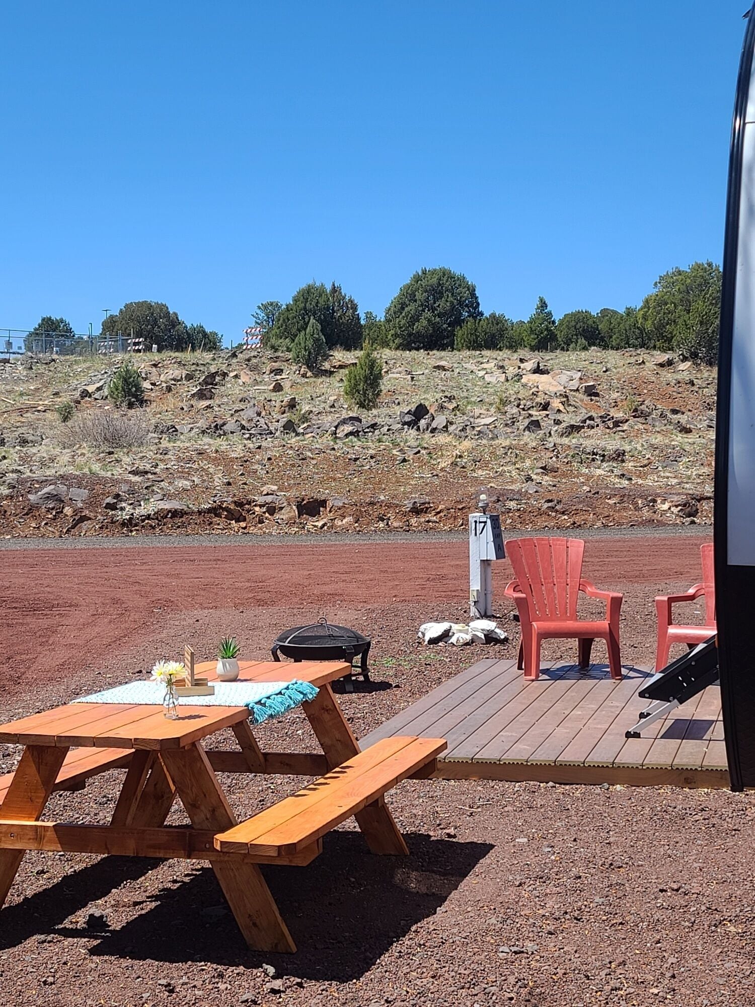 A wooden deck with picnic tables and red chairs, a barbecue grill, and a mailbox marked '17'.