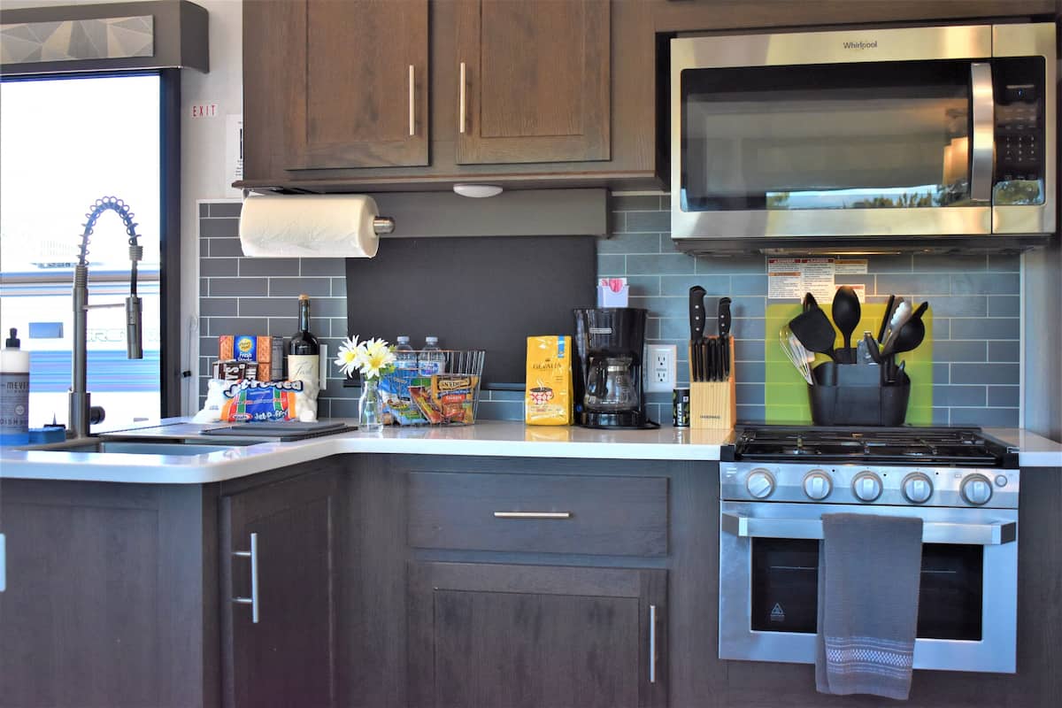 A modern kitchen with a stainless steel stove, a microwave, and wooden cabinets.