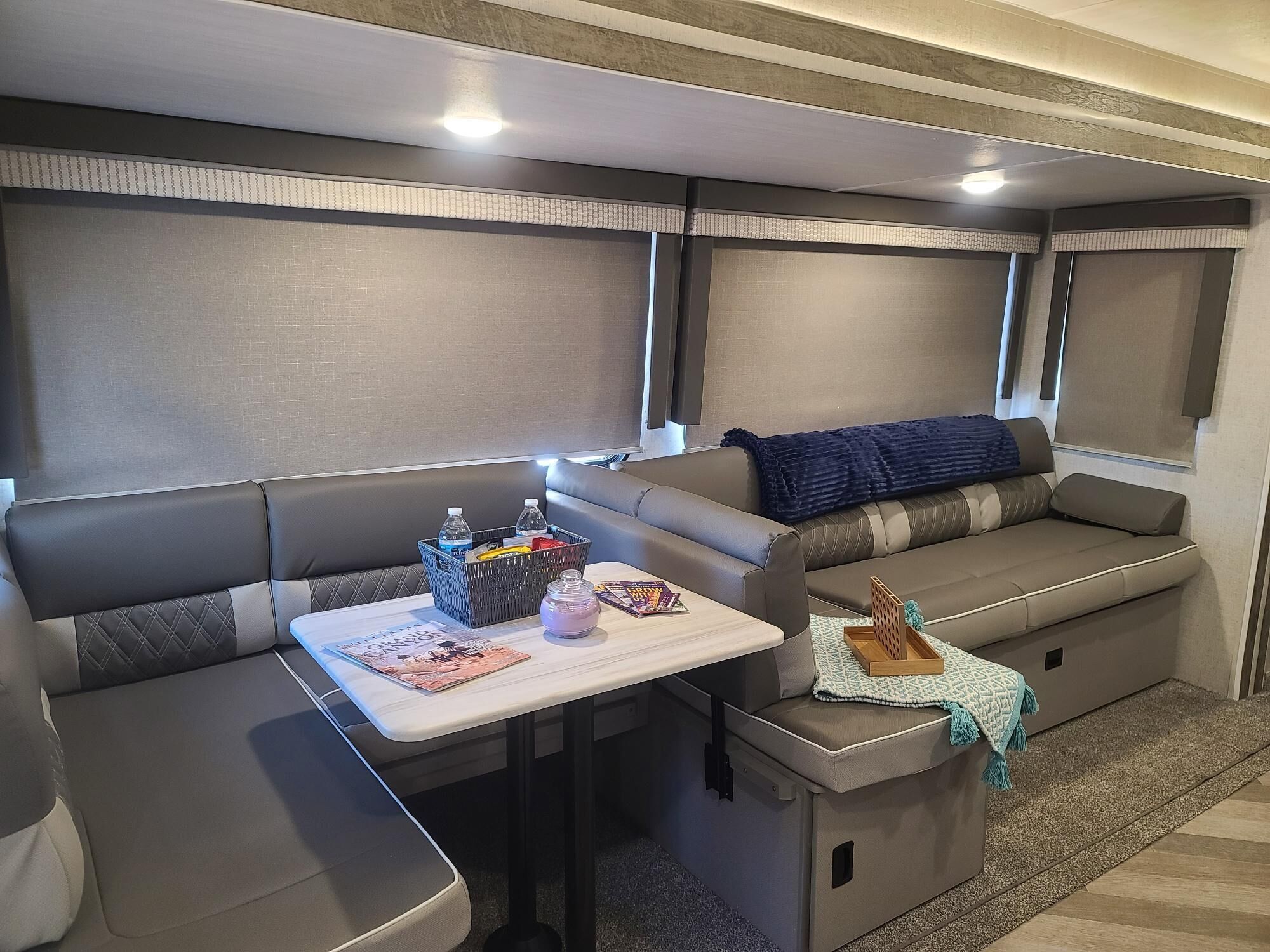A compact RV interior with a sofa, a small table with a basket, and a blanket.