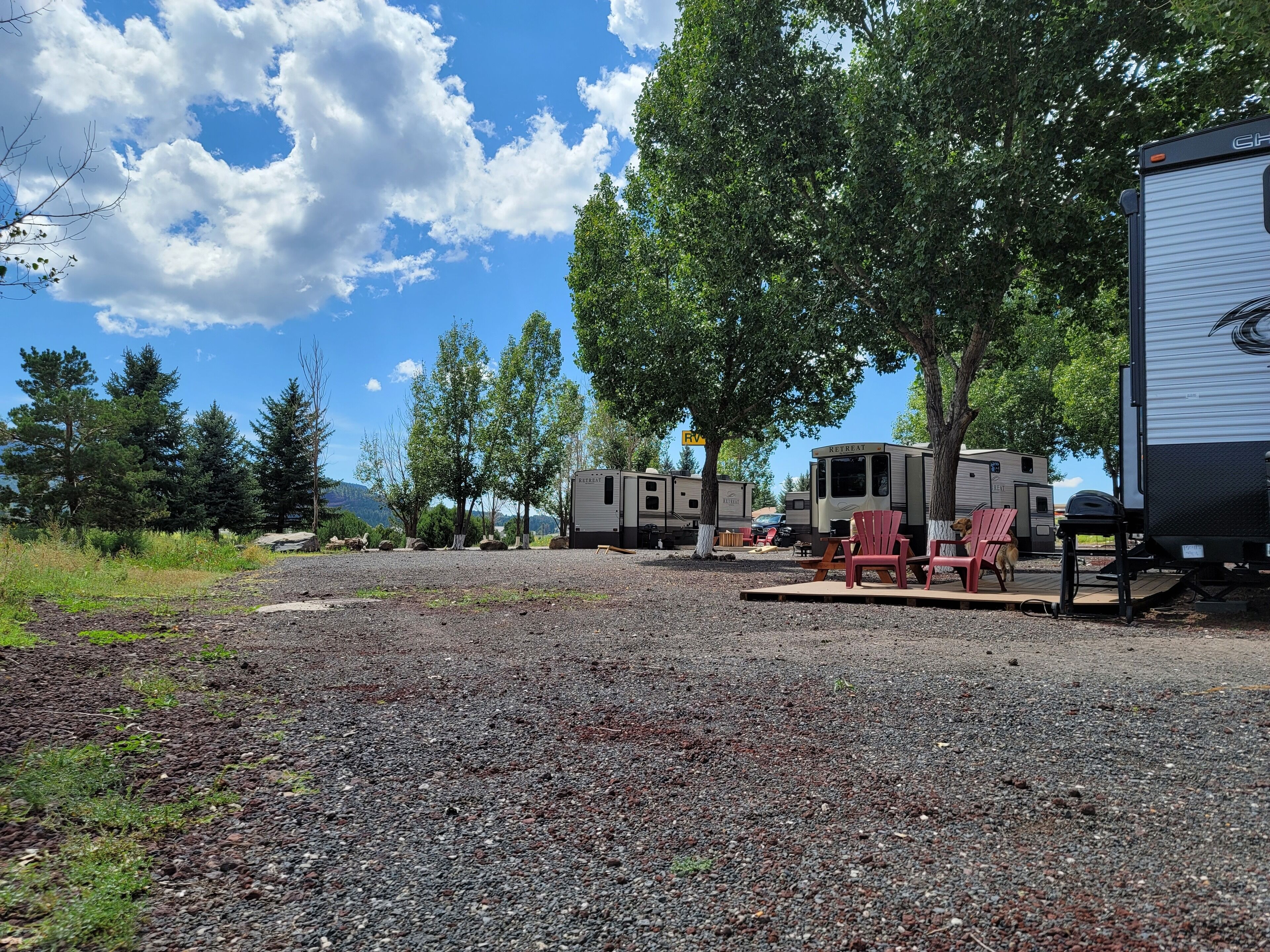 A campground with RVs, a retreat trailer, and outdoor seating.