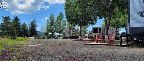 A campground with RVs, a retreat trailer, and outdoor seating.