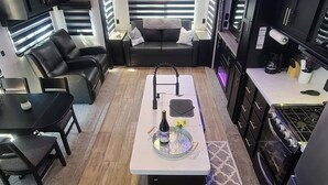 A compact kitchen with a central island, black cabinetry, and a modern design. - Grand Canyon RV Glamping (Williams)