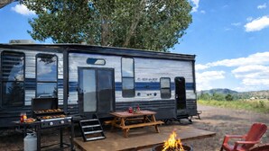 A recreational vehicle with a grill, a fire pit, and a picnic table. - Grand Canyon RV Glamping (Williams)