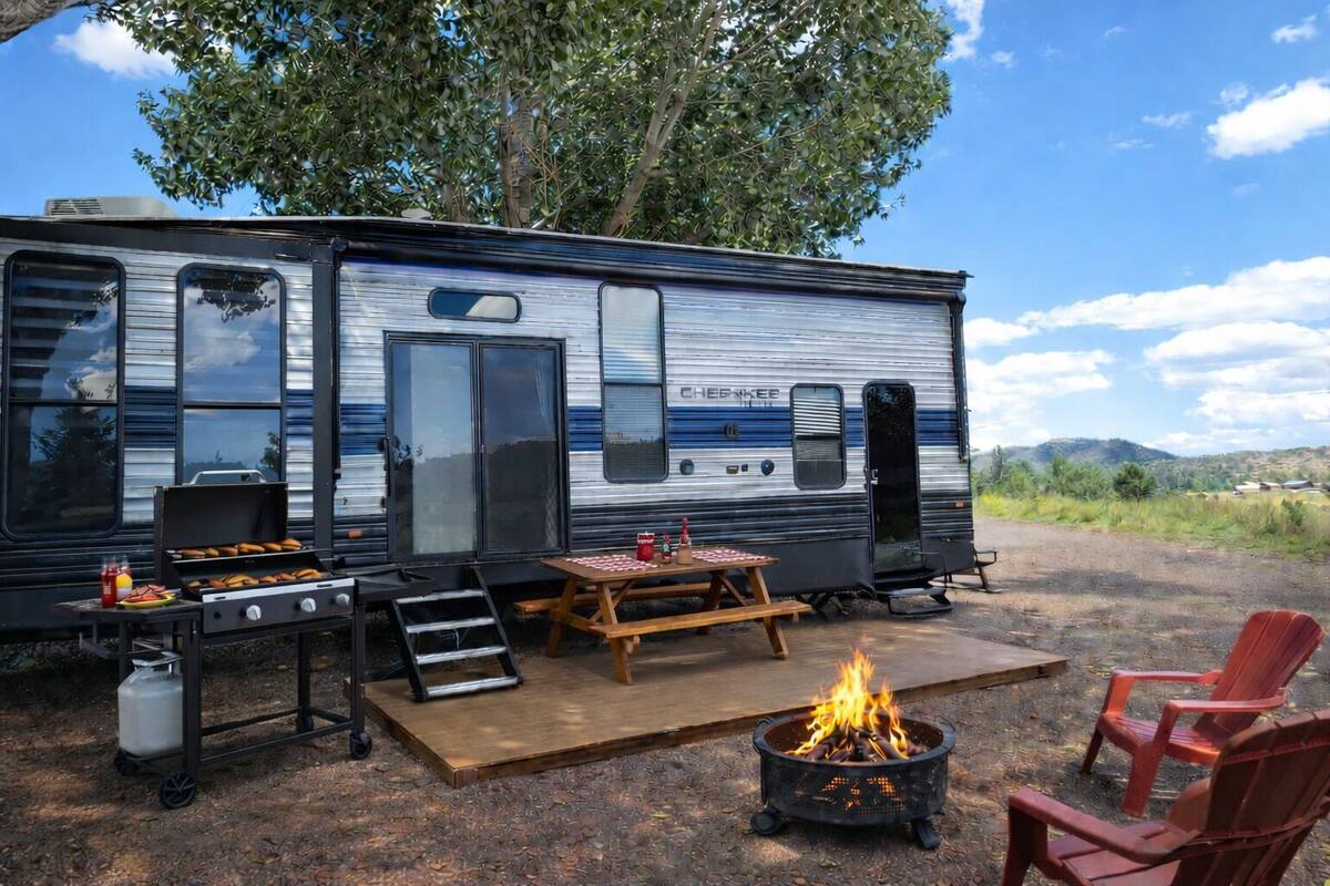 A recreational vehicle with a grill, a fire pit, and a picnic table.