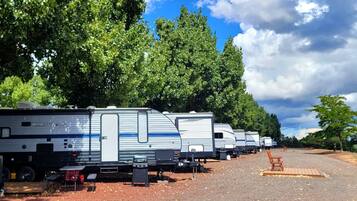 A row of RVs parked in a lot with trees in the background.