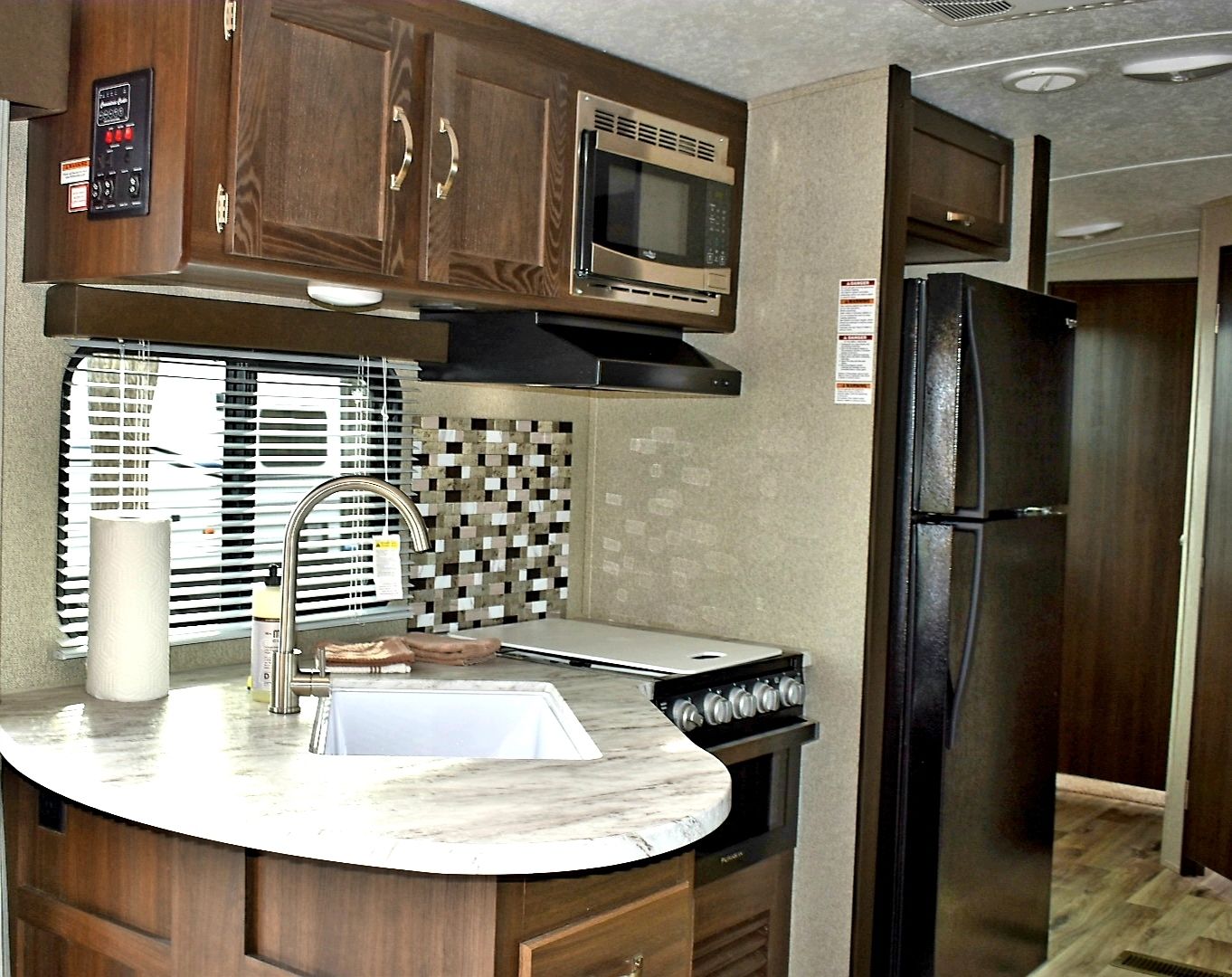 A compact kitchen with a microwave, stove, sink, and refrigerator.