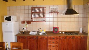 Une cuisine avec des meubles de rangement en bois, un four à micro-ondes encastré, un évier et une cuisinière à gaz.