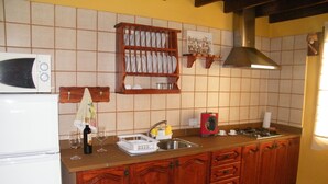 Une cuisine avec des meubles de rangement en bois, un réfrigérateur blanc, un four à micro-ondes, un évier et une cuisinière.
