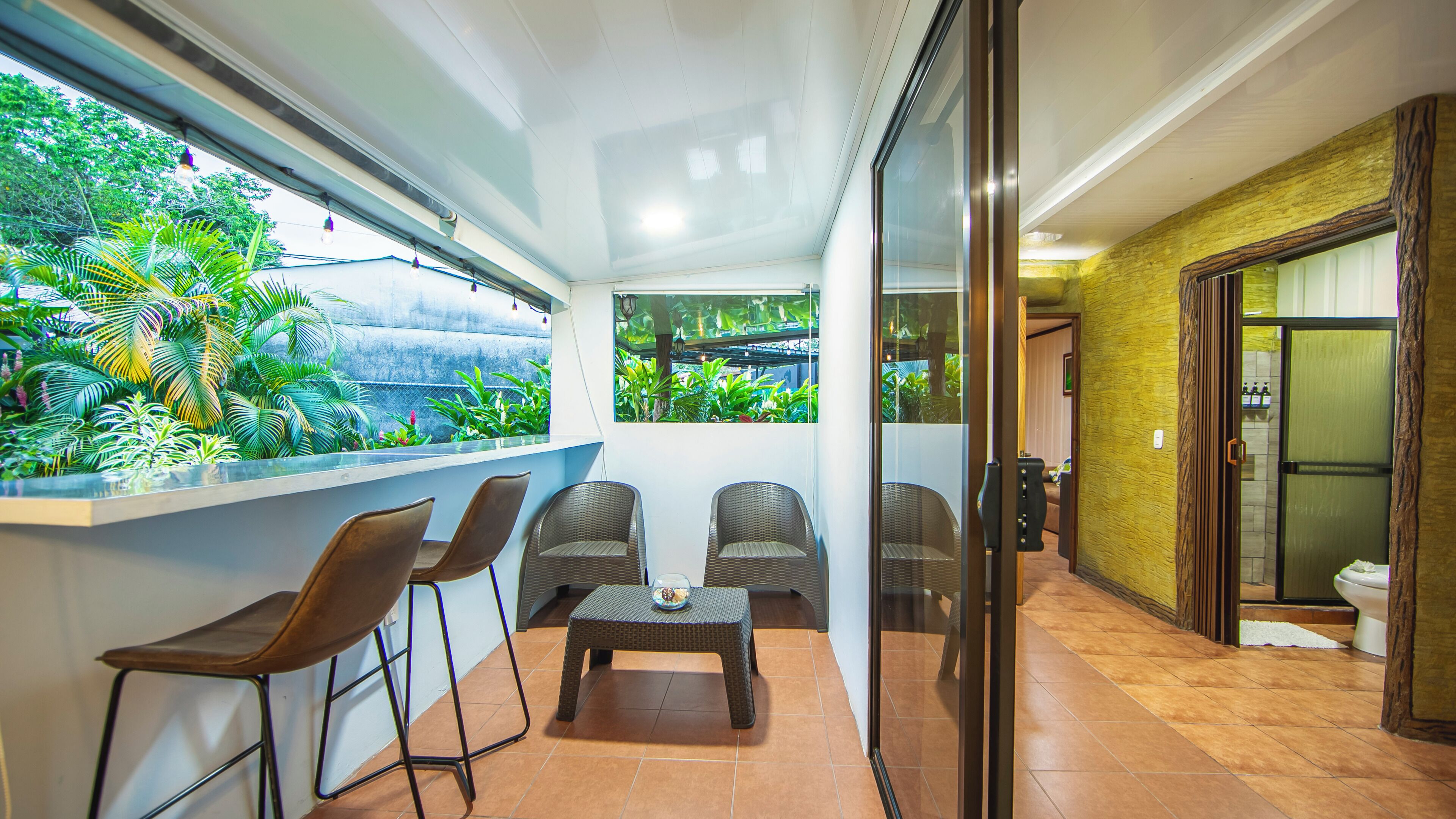 A balcony with chairs, a table, and a view of greenery.