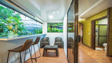 A balcony with chairs, a table, and a view of greenery.