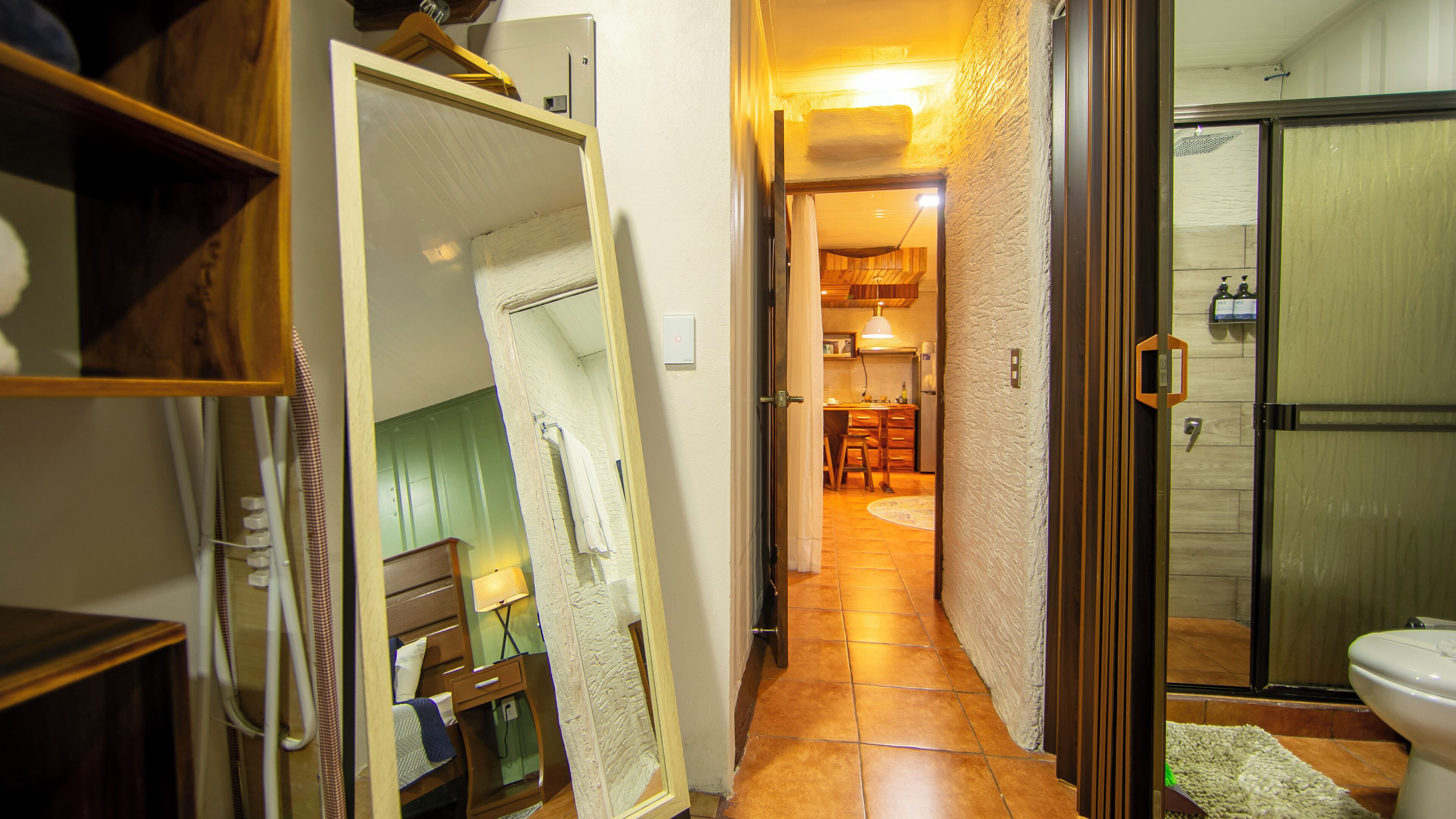 A narrow hallway leading to a bathroom with a shower and toilet.