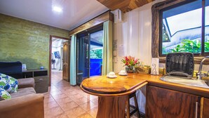 Um saguão de hotel com uma receção de madeira, um sofá, uma estação de café e vista para o exterior arborizado.