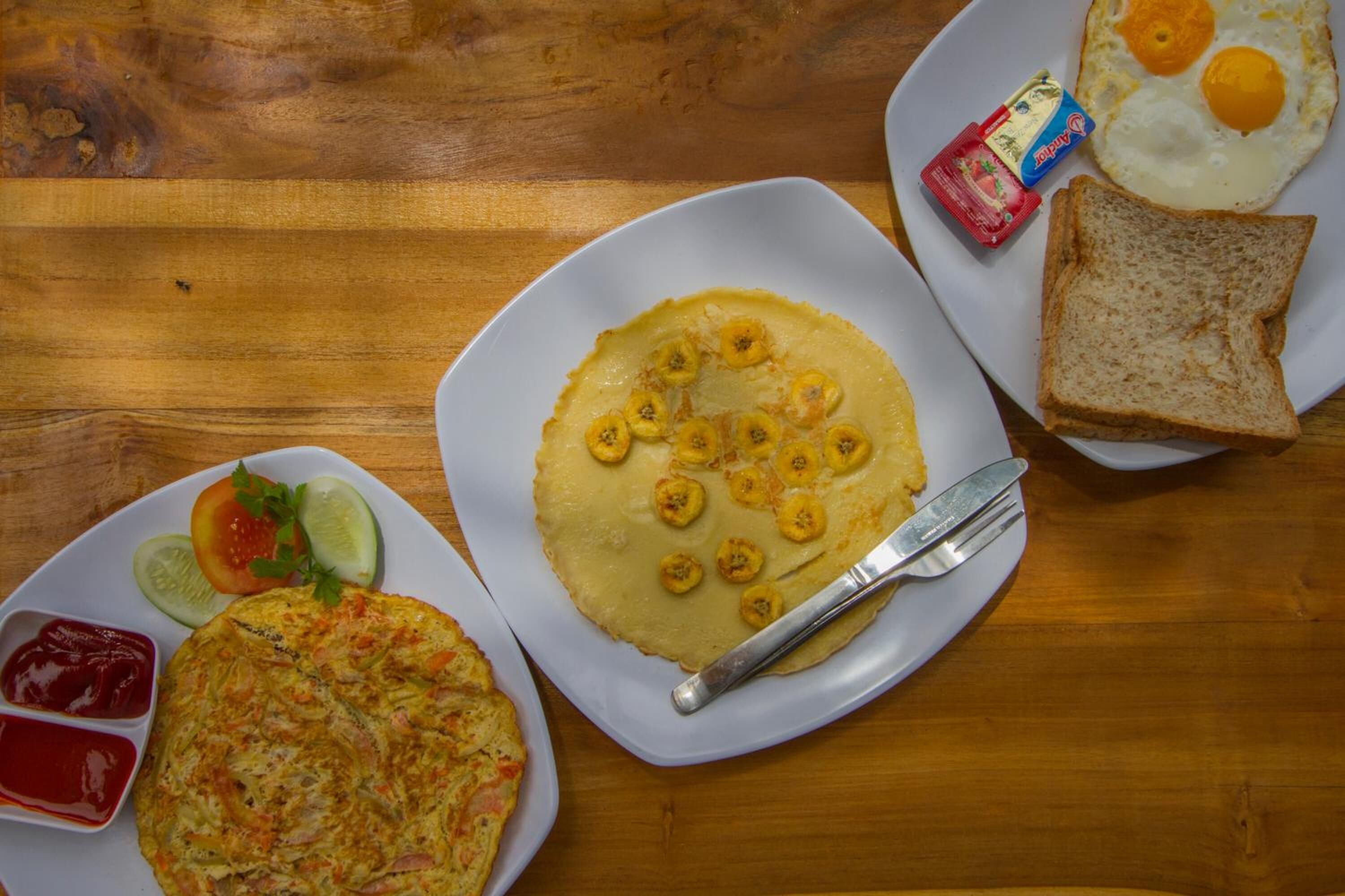 Een ontbijt bord met eieren, toast en een pannenkoek, vergezeld van groenten en toevoegingen.
